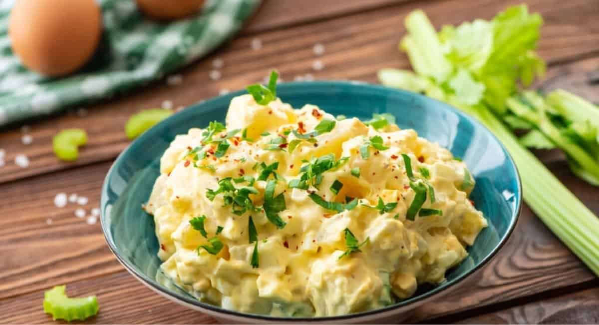 Overhead image of potato salad recipe with garnish in blue bowl.