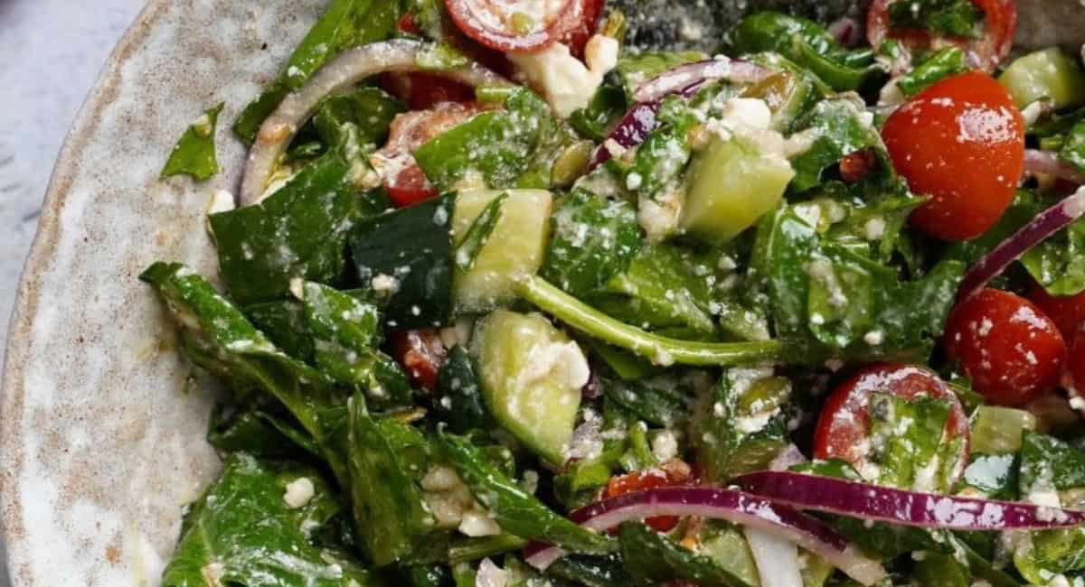 Up close image of spinach tomato salad with feta cheese.