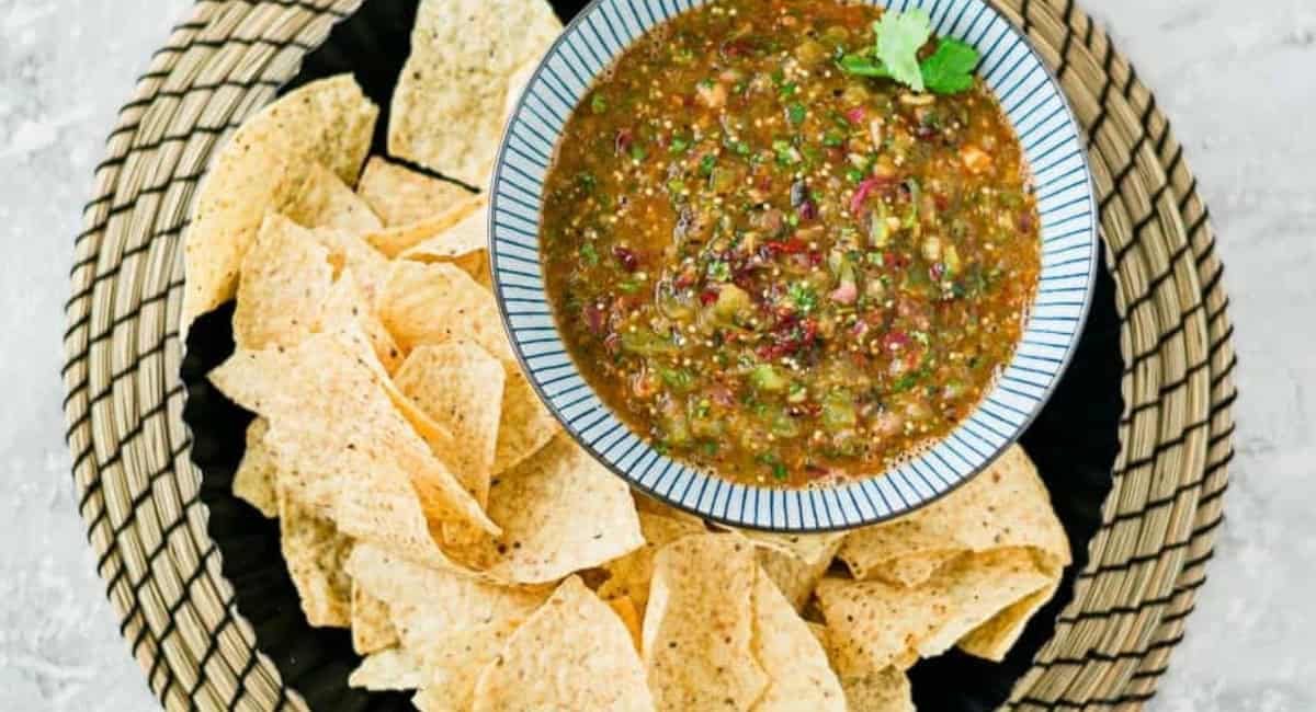 Overhead image of tomatillo-chipotle salsa with tortilla chips on the side.