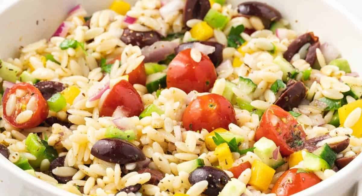 Overhead image of orzo pasta salad with honey dijon dressing in white bowl.