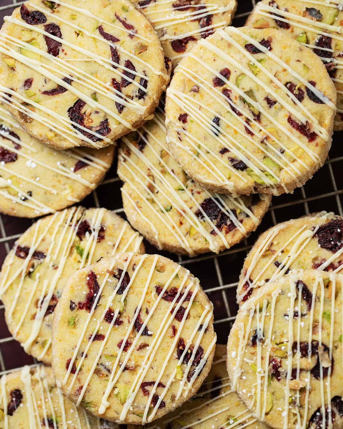 Up close image of cranberry pistachio shortbread cookies with white chocolate drizzle.