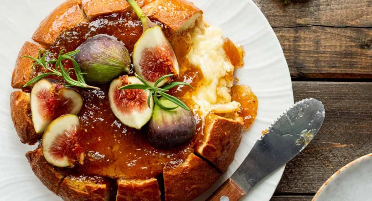 Overhead image of bread bowl baked brie with fig preserves.