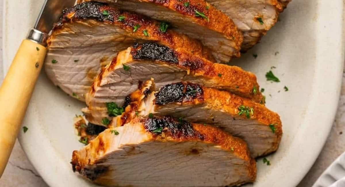 Up close image of air fryer pork roast recipe with garnish on white dish.