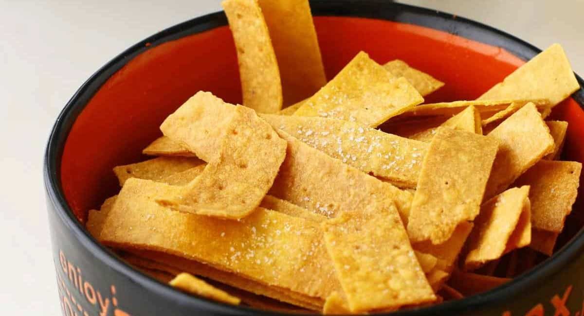 Up close image of air fryer tortilla strips in red and black bowl.