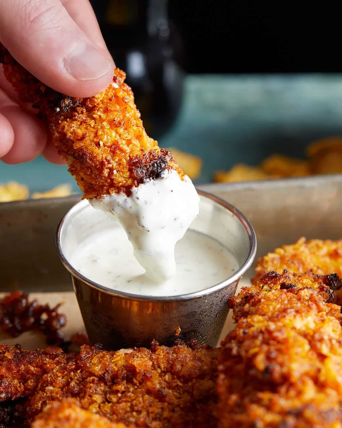 Up close picture of air fryer cornflake chicken dipped in ranch.