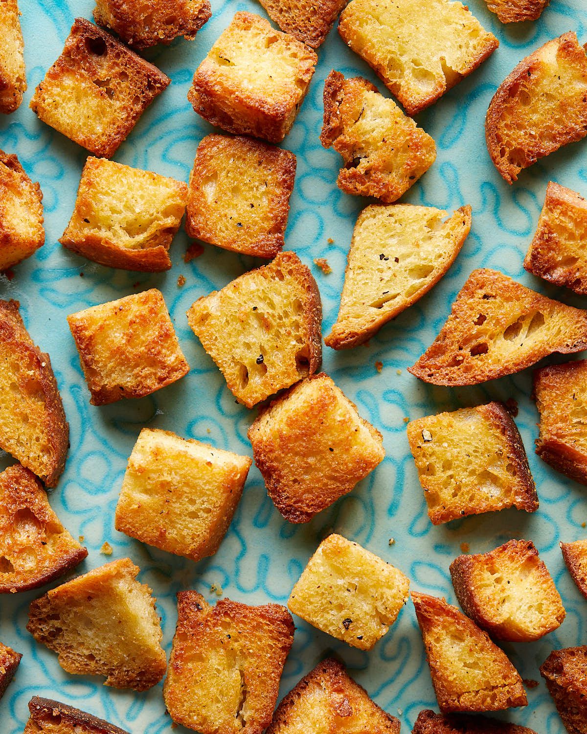 Overhead up close image of air fryer croutons on white dish.