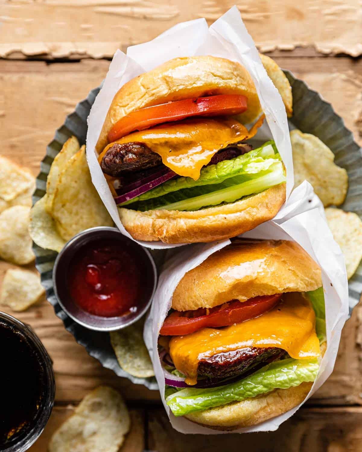 Overhead image of haburgers with toppings wrapped in parchment paper.