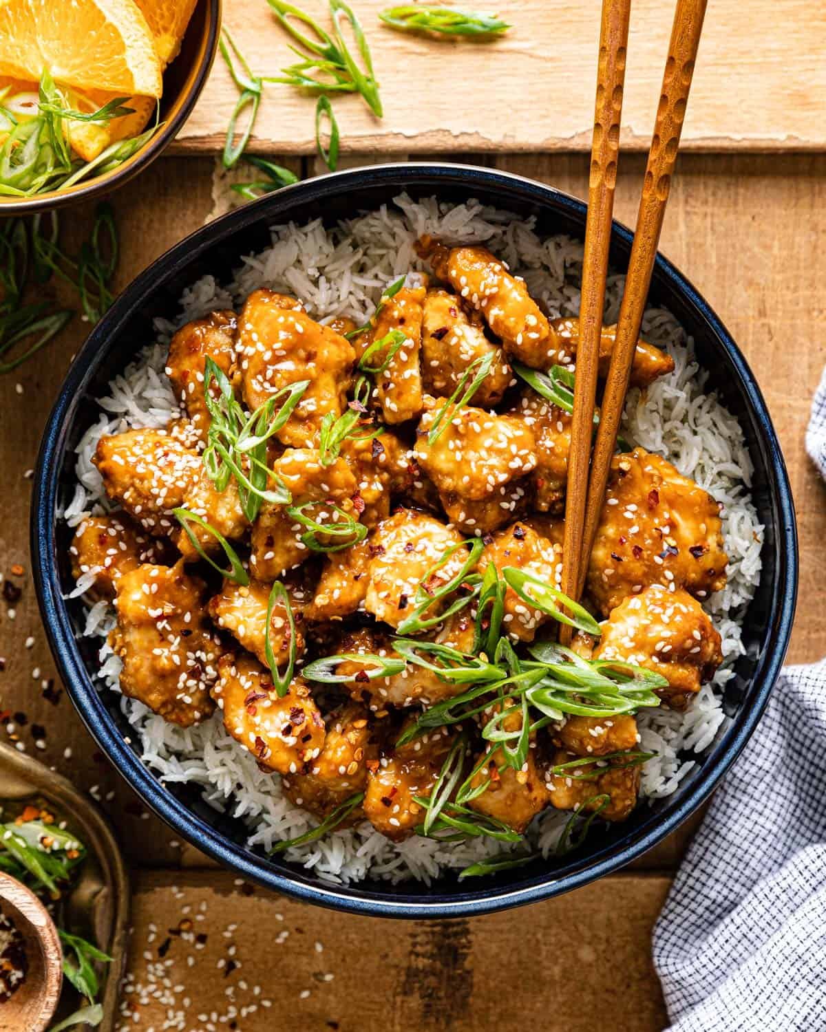Overhead image of air fryer orange chicken with garnish.