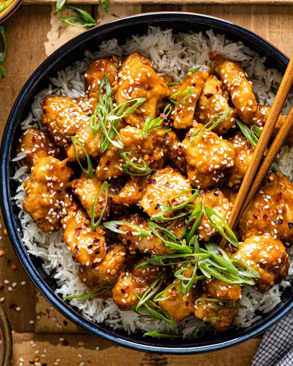 Up close overhead image of air fryer orange chicken with garnish.