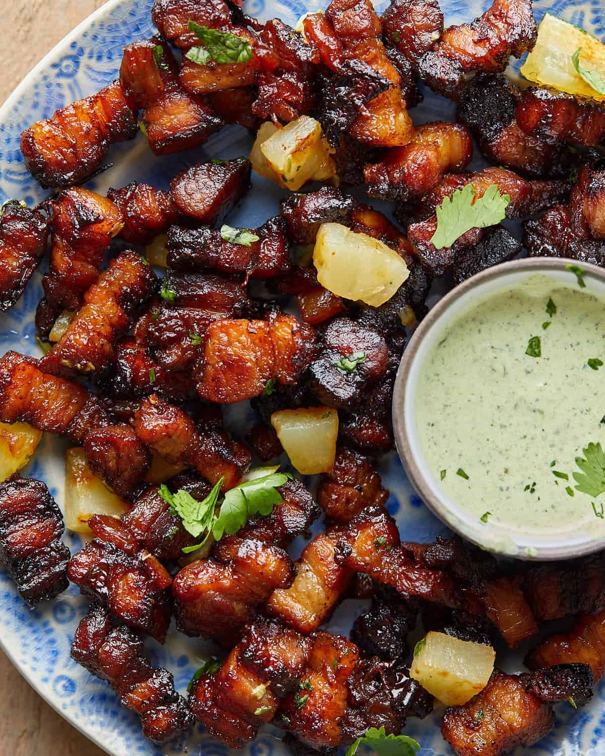 Overhead image of air fryer pork belly bites with garnish.