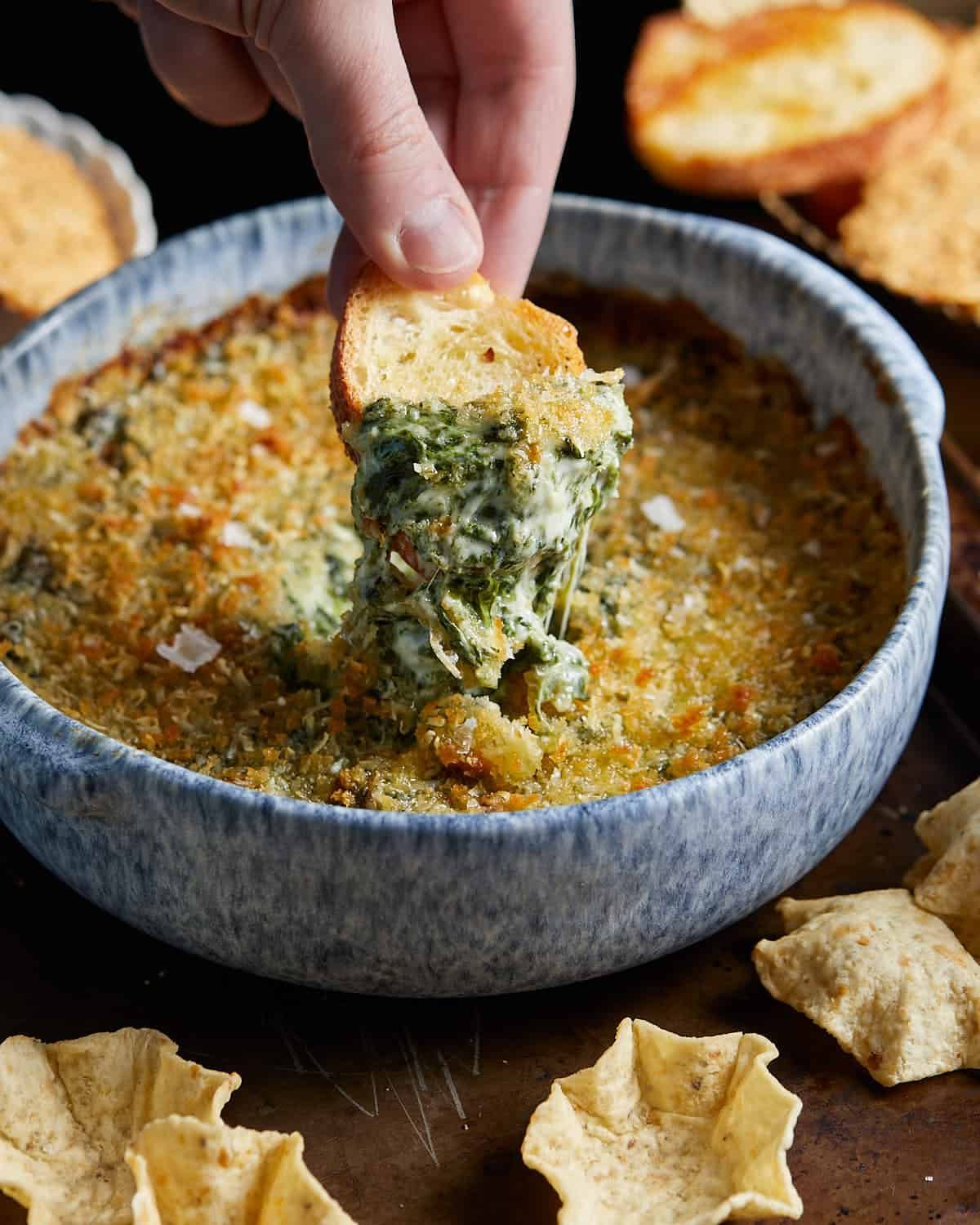 Photo of bread being dipped into air fryer spinach dip.