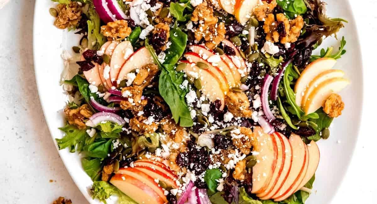 Overhead image of apple walnut salad on white dish with garnish.