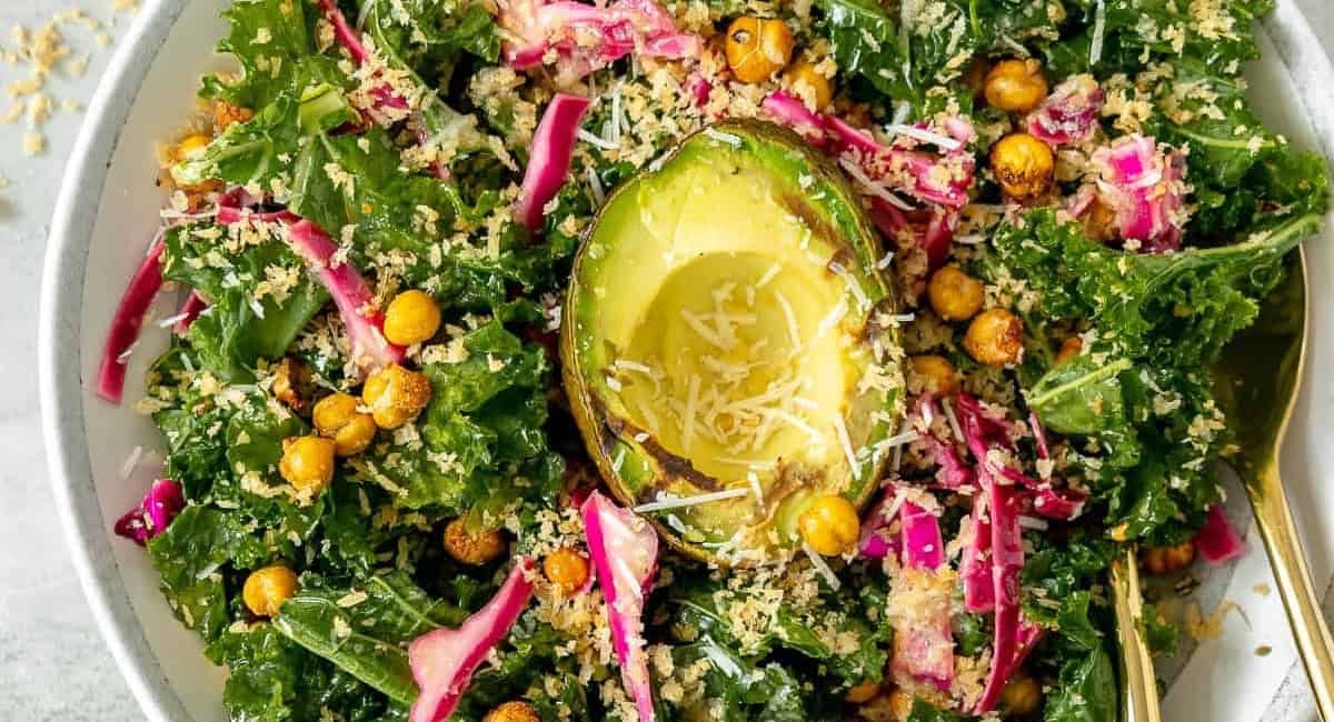 Overhead image of avocado kale salad in white bowl.