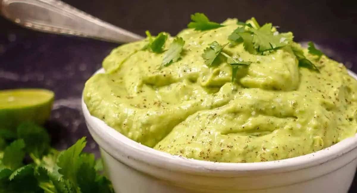 Up close image of avocado lime crema with garnish.