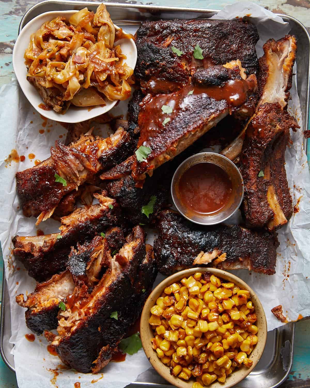 Overhead image of baby back ribs with side dishes and sauce.