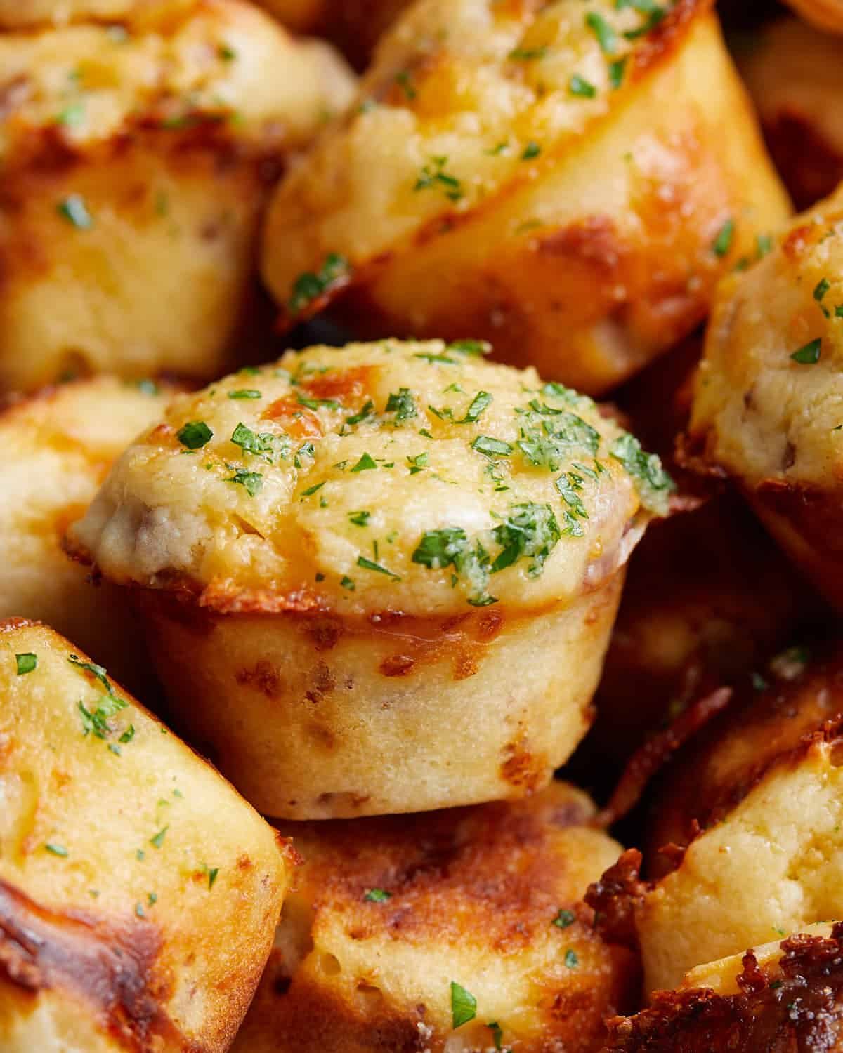Up close image of bacon and cheddar cheese muffin with garnish.
