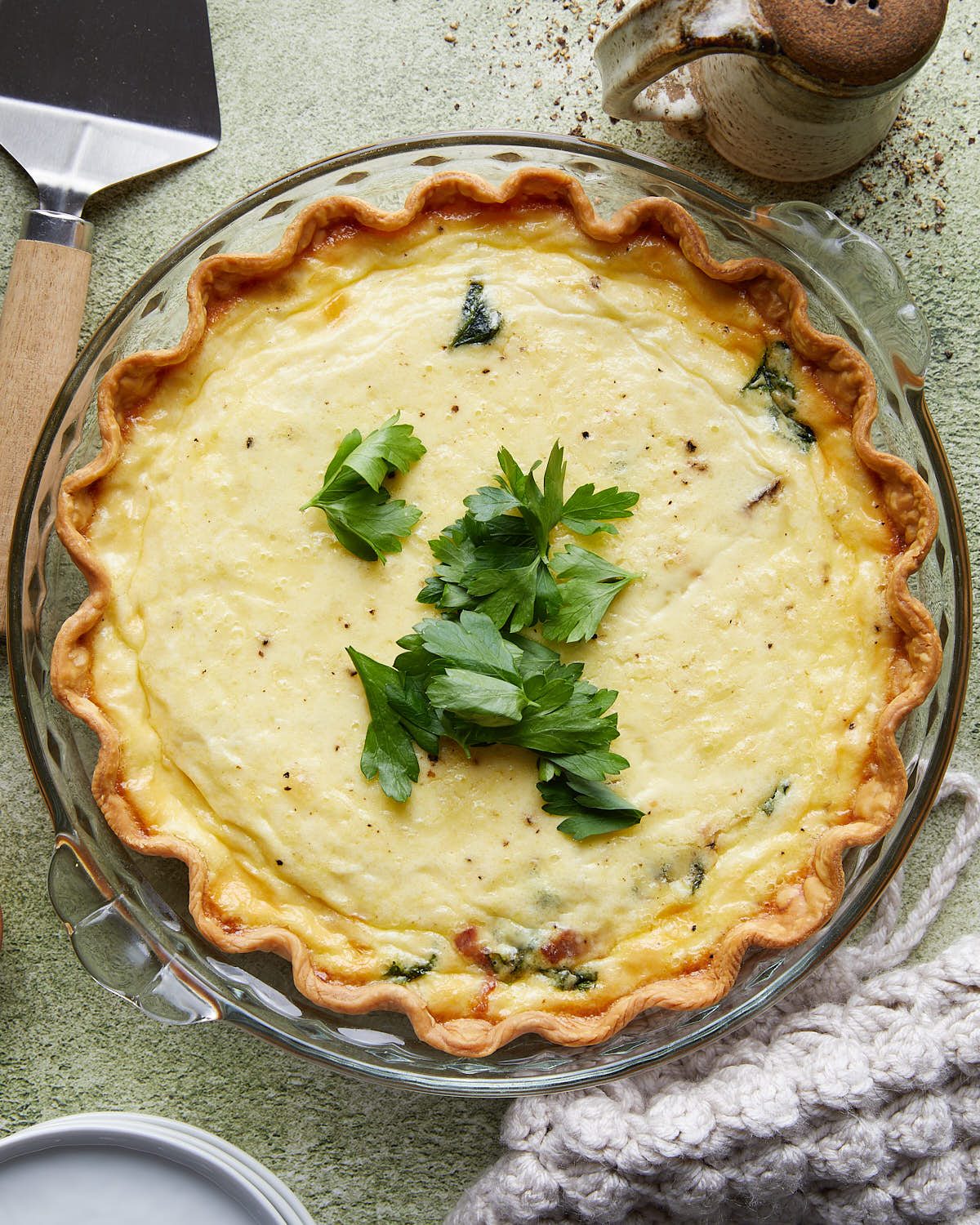 Overhead image of homemade bacon mushroom spinach quiche with a golden flaky crust, creamy egg filling, crispy bacon, sautéed mushrooms, and spinach.