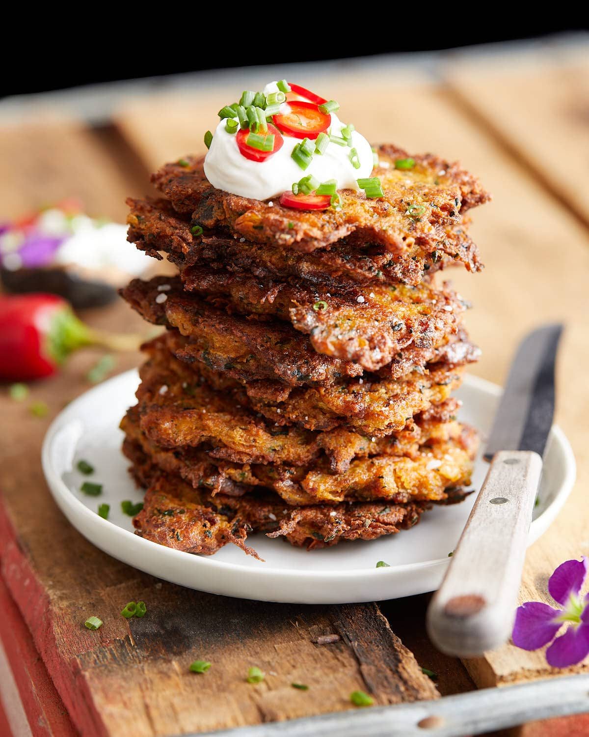 Image of stacked bacon zucchini fritters with garnish.