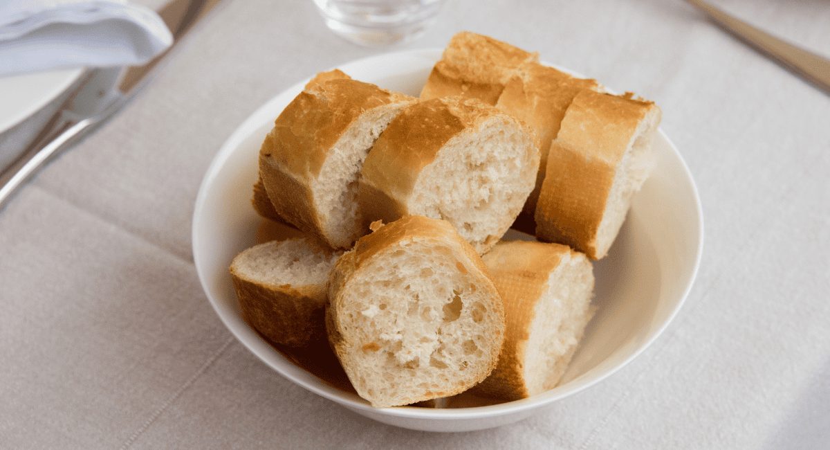 Up close photos of baguette sliced in white bowl.