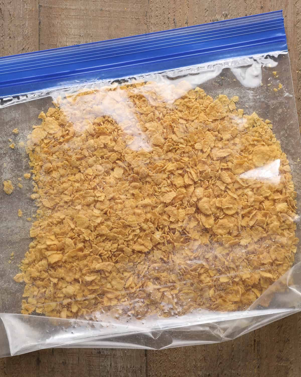 Cornflakes crushed into coarse crumbs in a zip-top bag.