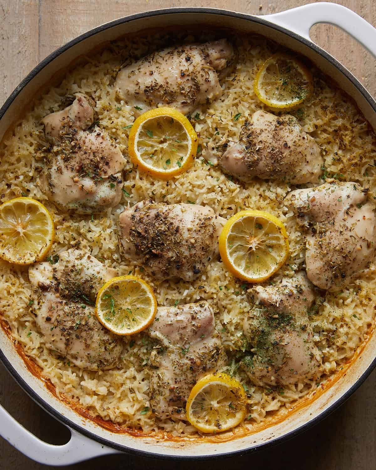 Baked lemon chicken and rice with cooked chicken thighs, tender rice, lemon slices, and herbs.