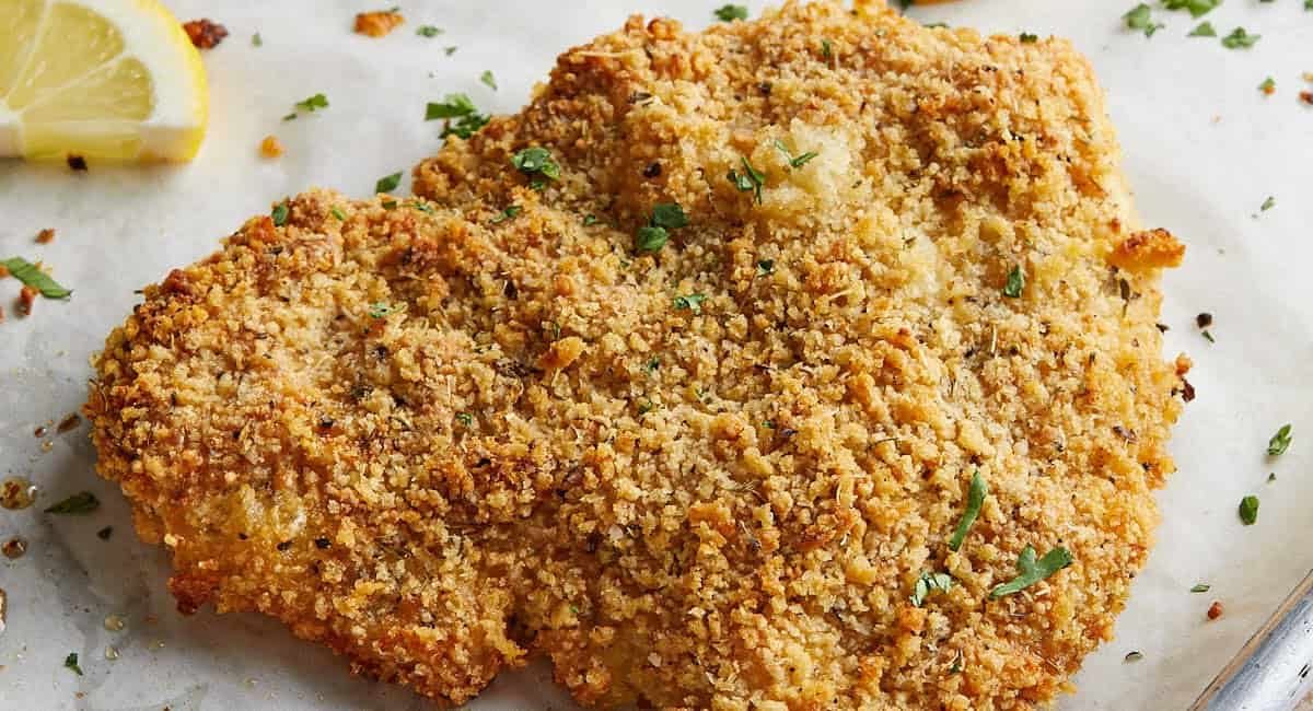 Overhead image of baked chicken cutlets with garnish.