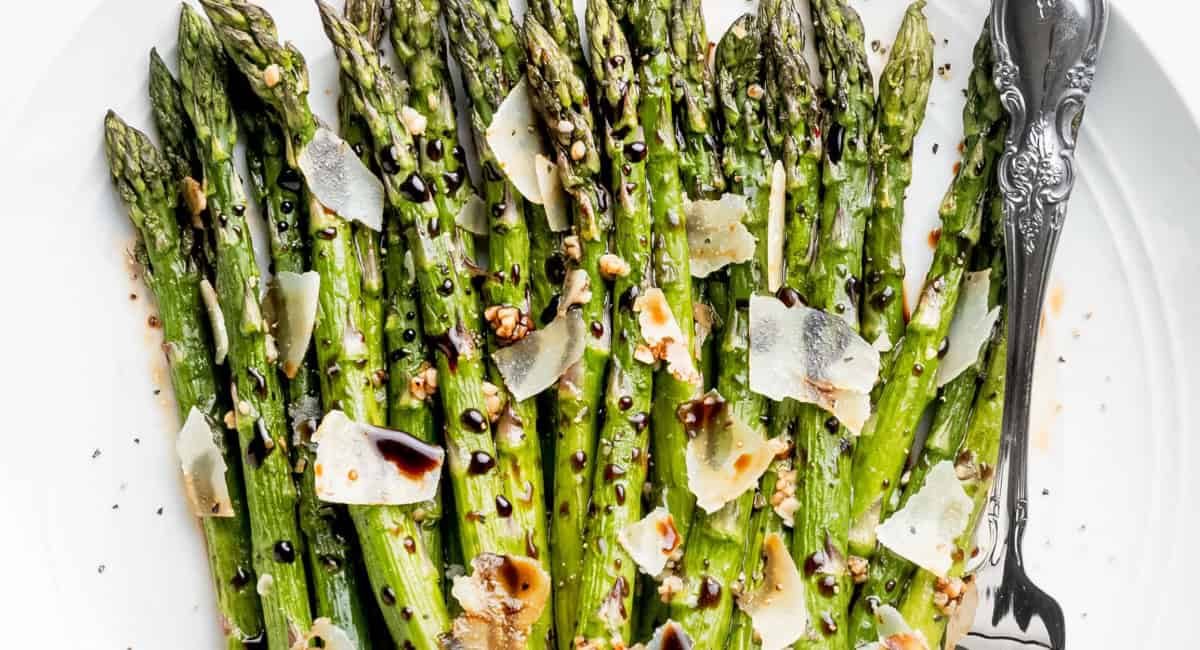Overhead image of roasted asparagus with balsamic vinegar glaze with garnish.