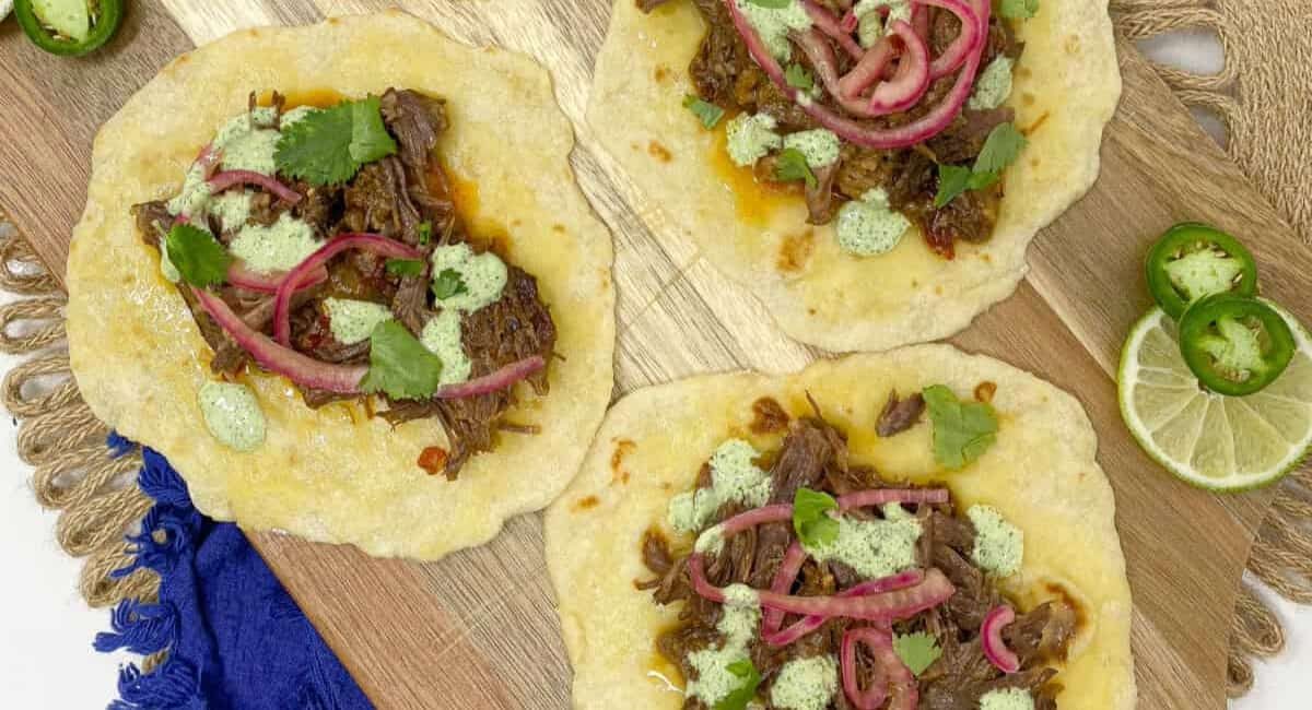 Overhead image of barbacoa tacos with garnish.