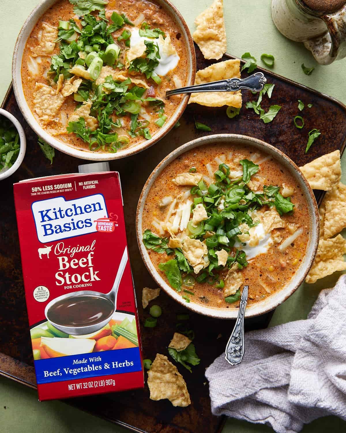 Ground beef enchilada soup with a kitchen basics beef broth carton next to the bowl.