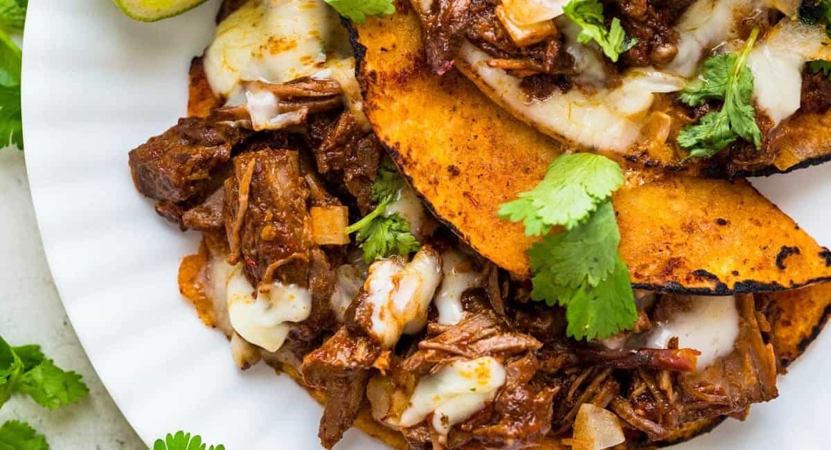 Overhead image of quesabirria tacos with garnish.