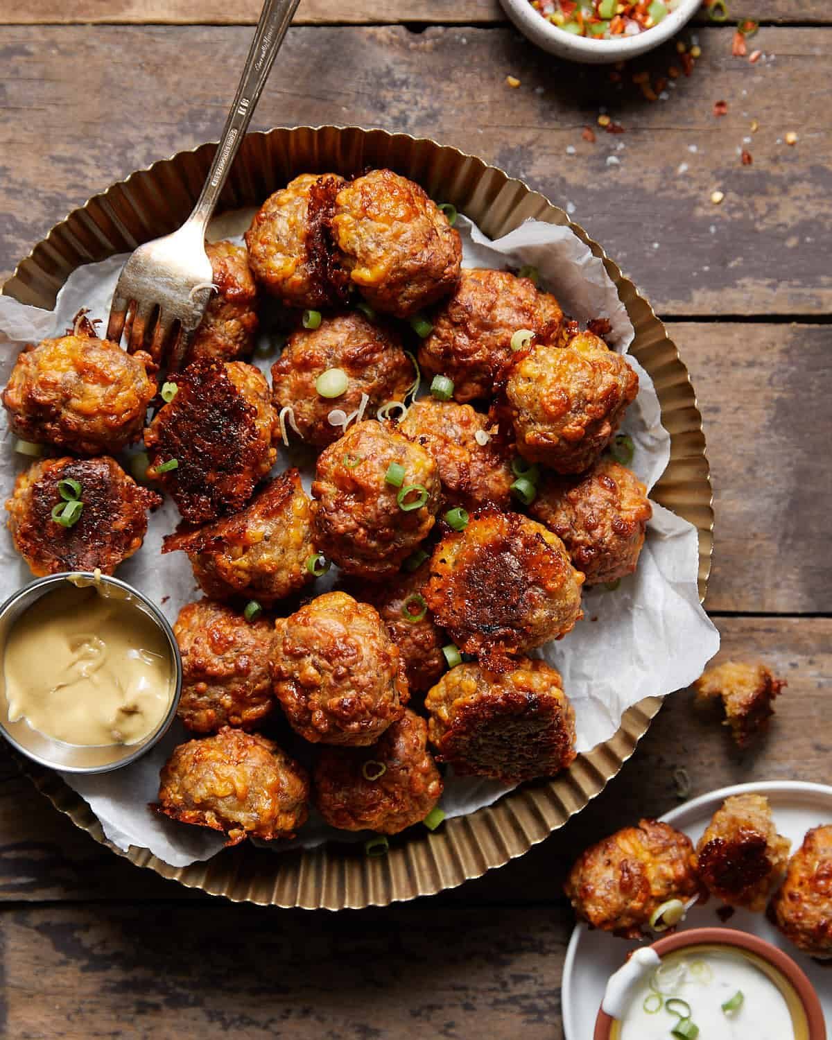 Tray of cheesy bisquick sausage balls with sauce.