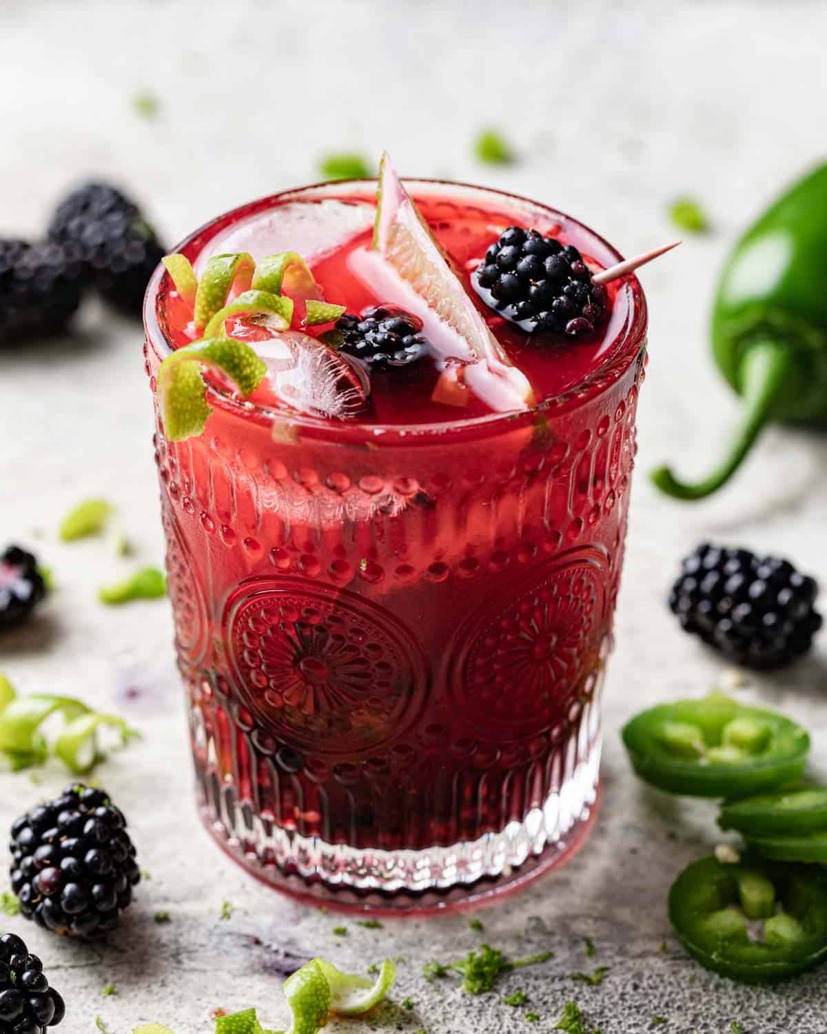 Upclose overhead image of blackberry jalapeno margarita with garnish.