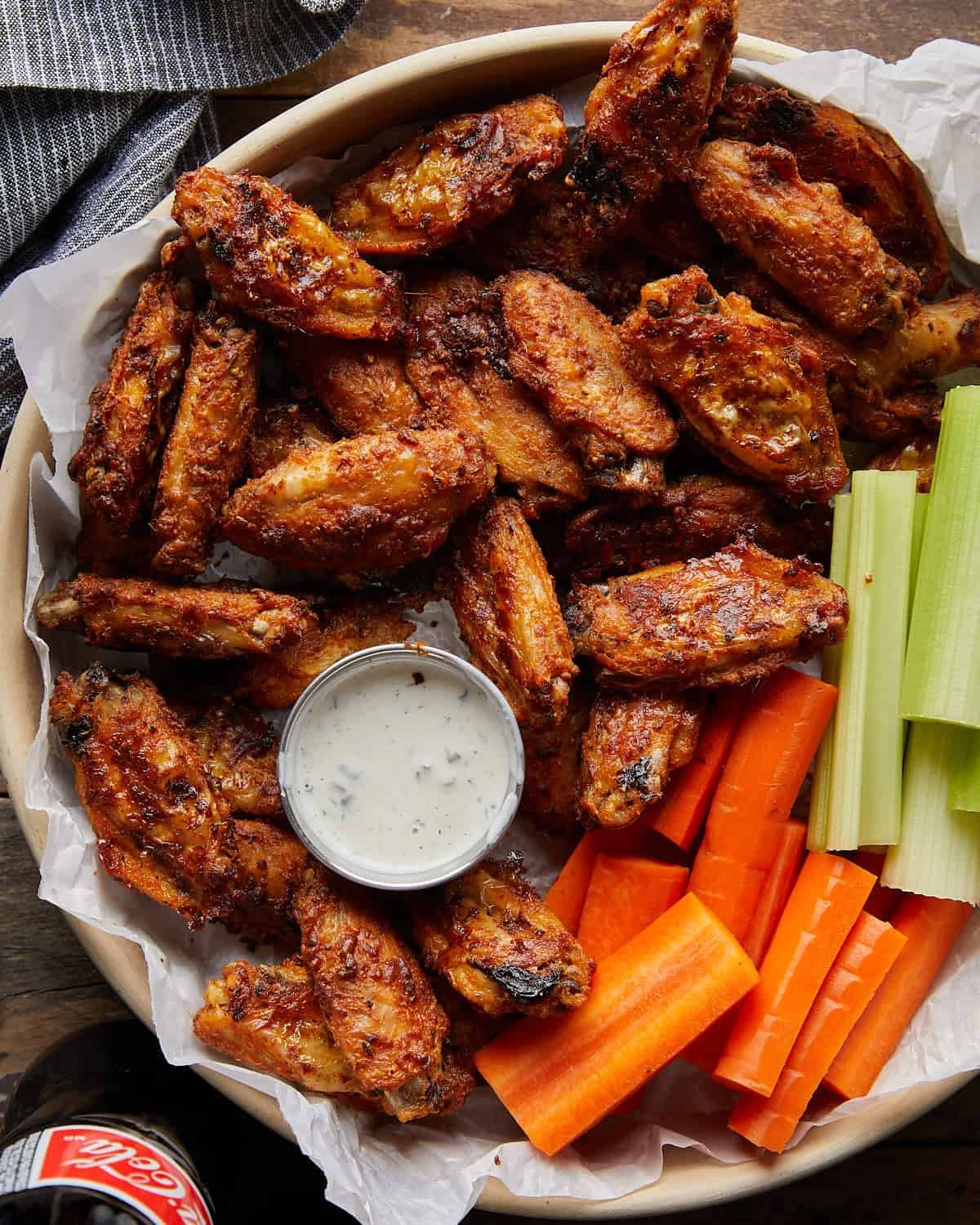 Overhead image of blackened wings with celery and carrot sticks, paired with ranch dressing.