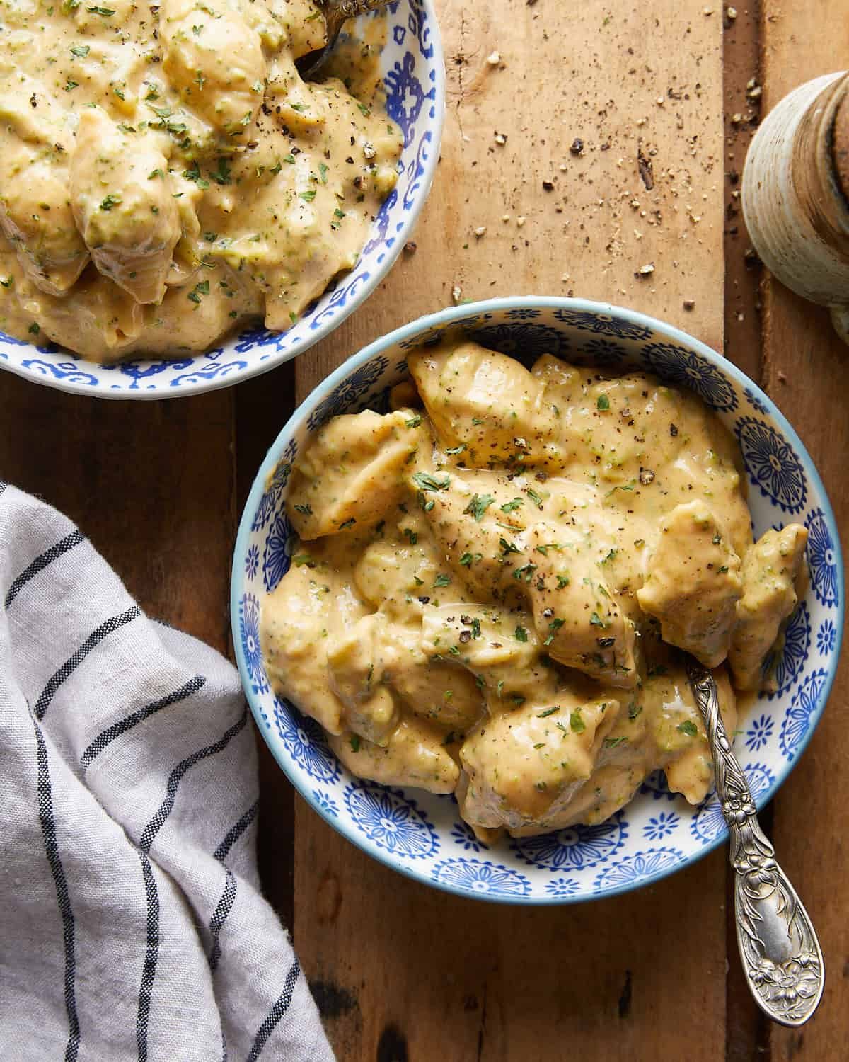 Overhead image of broccoli mac and cheese in two blue and white bowls with a silver spoon.