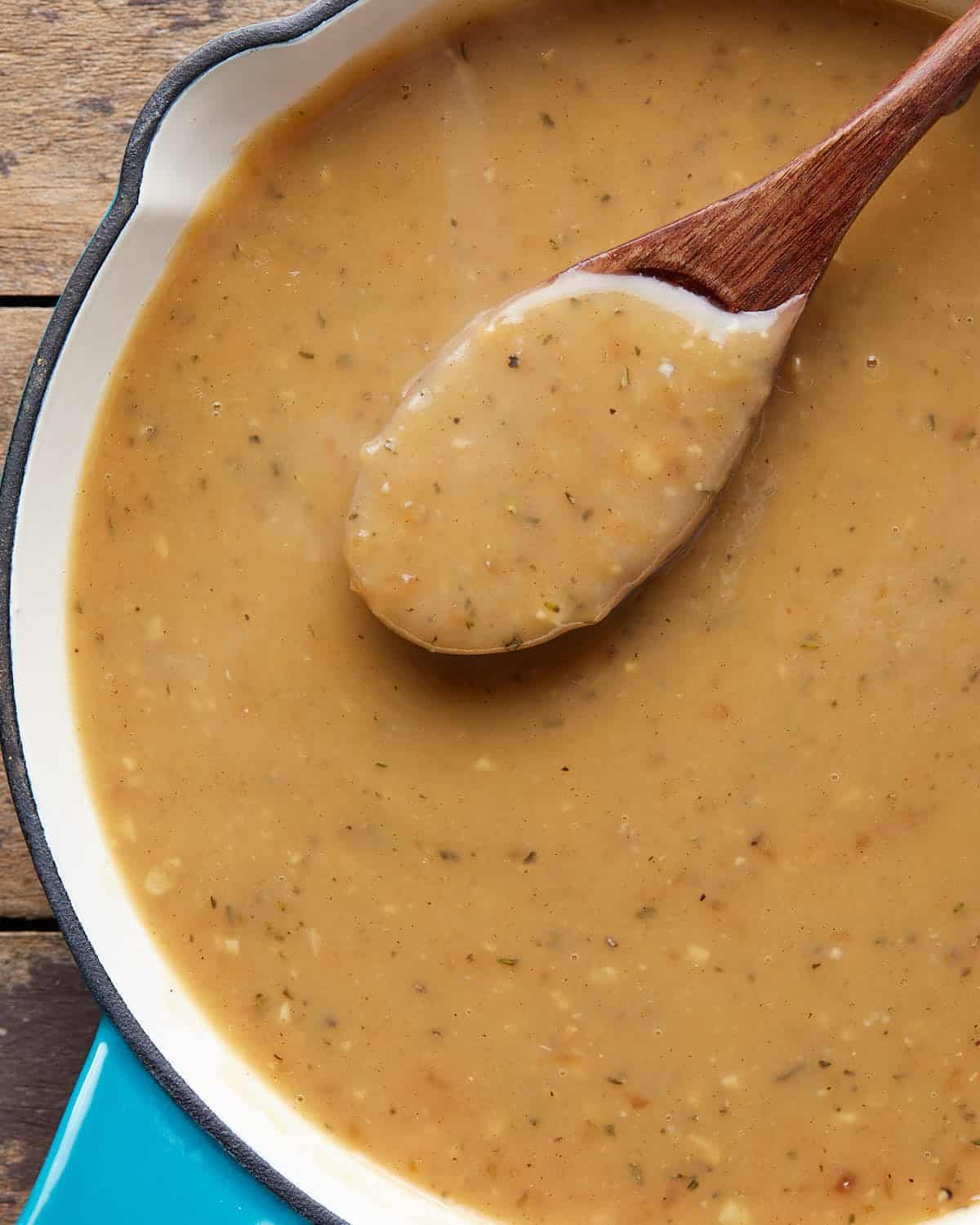 Up close image of brown gravy on wooden spoon.