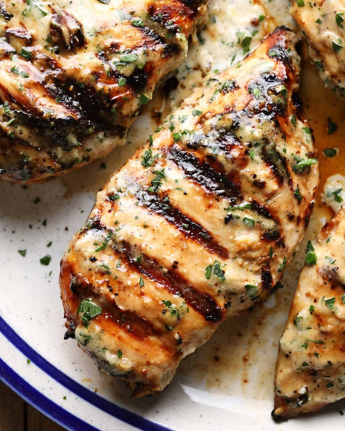 Close-up of sliced grilled Caesar chicken with grill marks and fresh herbs.