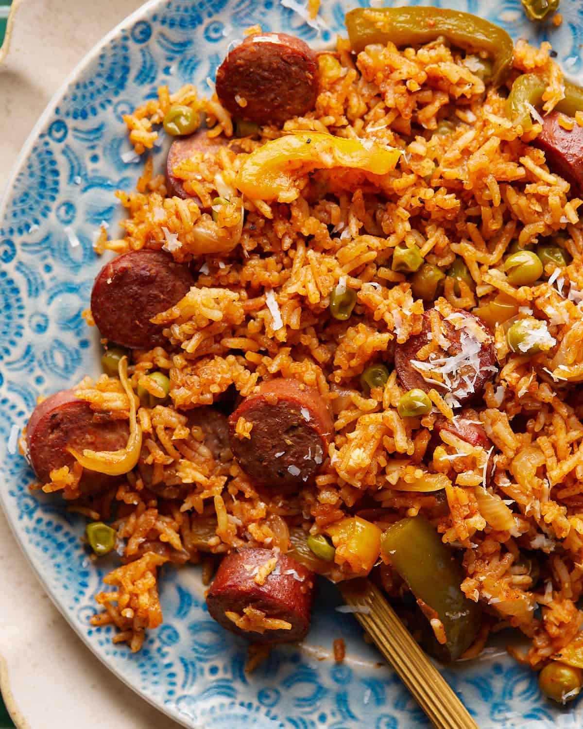 Close-up of Cajun sausage and rice with browned andouille, bell peppers, peas, and grated Parmesan.