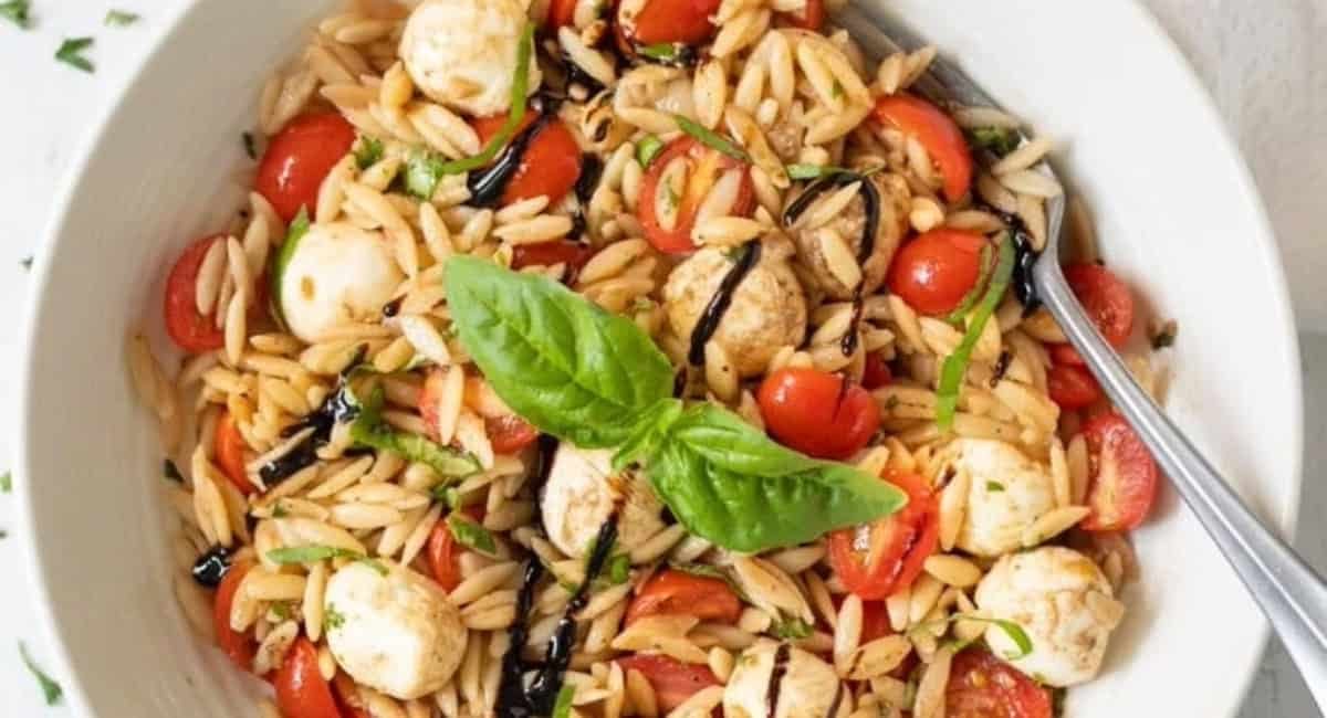 Overhead image of caprese orzo pasta salad with garnish.
