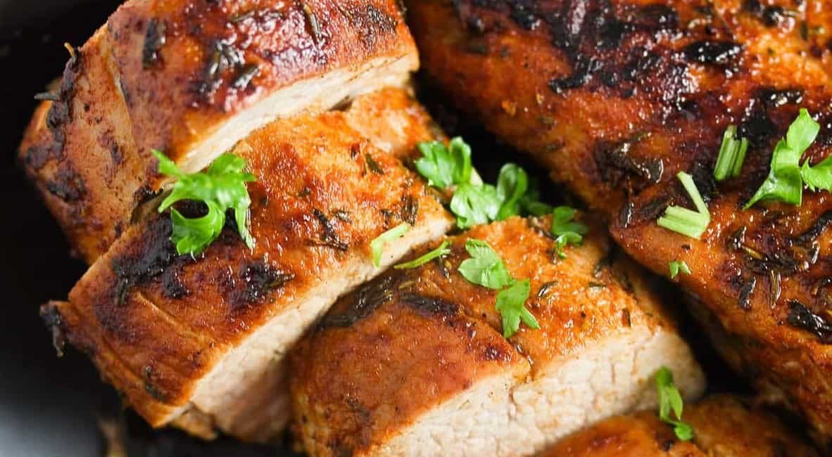 Up close image of cast iron pork loin with garnish.