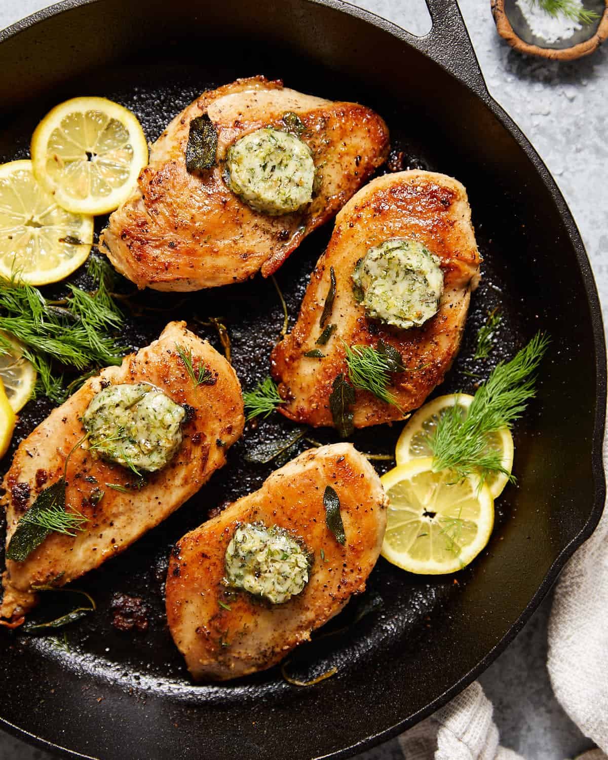 Overhead shot to show finished cast iron skillet chicken breast with butter on top.