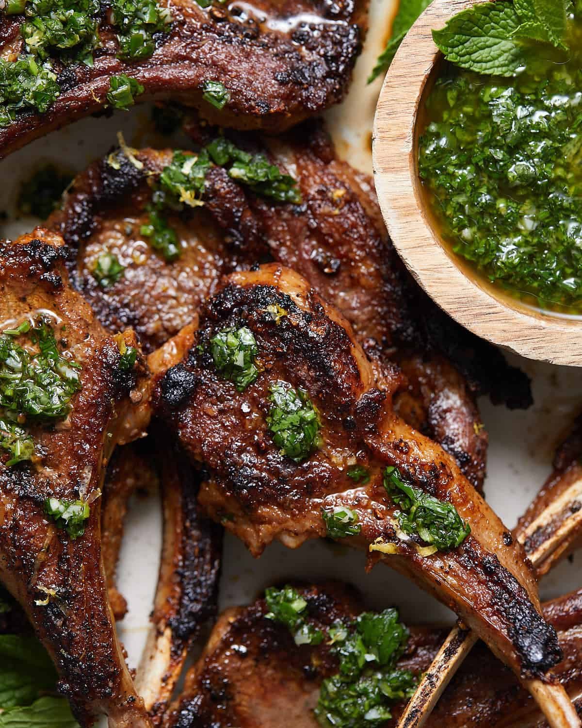Up close image of lamb chops on serving dish with garnish.