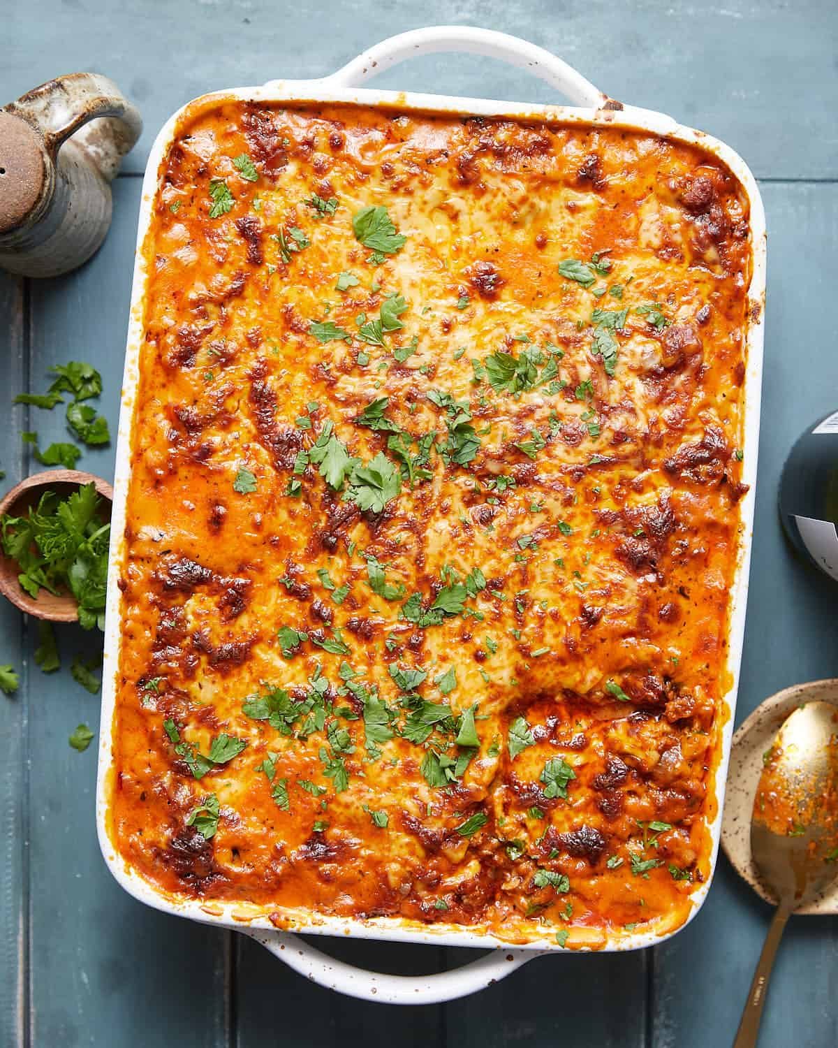 Overhead image of cheesy baked spaghetti with garnish.