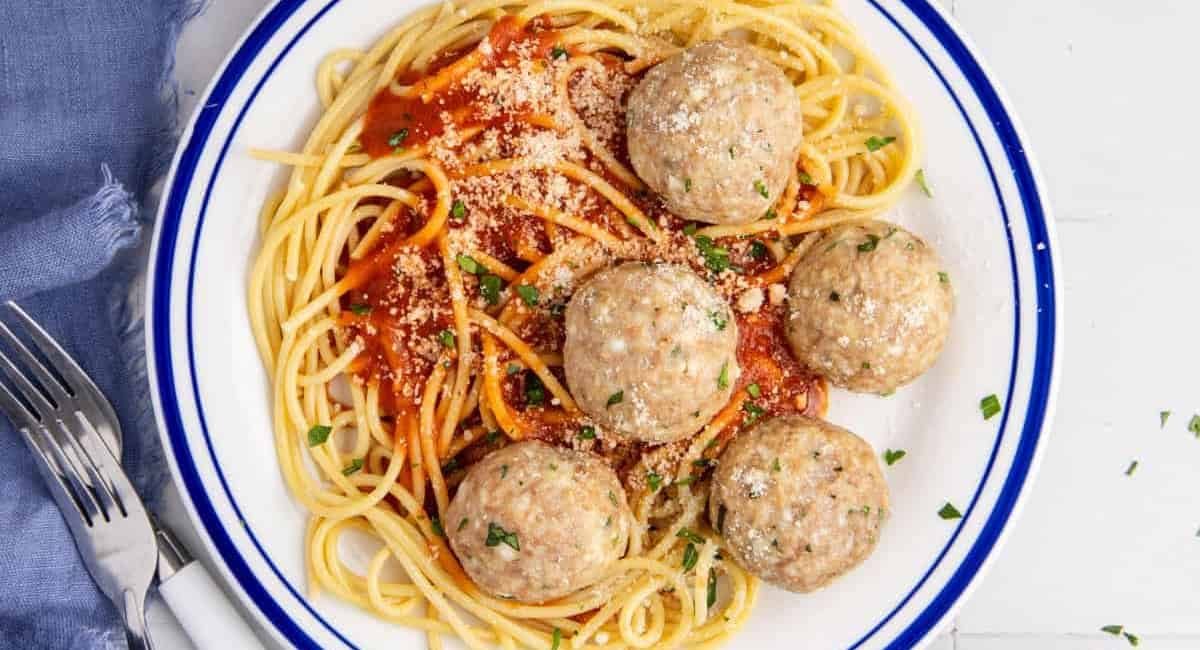Overhead image of chicken rocotta meatballs with spaghetti on white and blue plate.