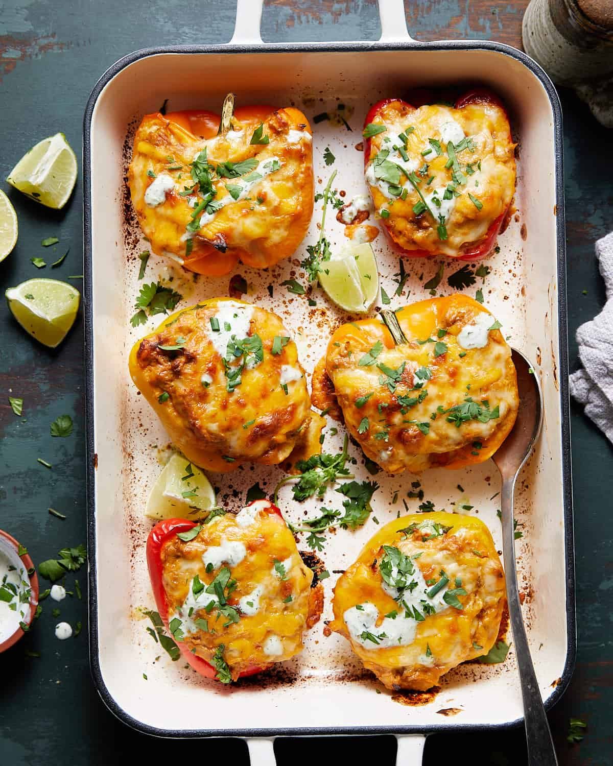 Six cheese & chicken stuffed bell peppers in a baking dish.