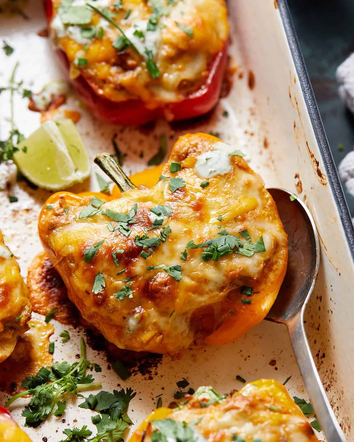 A stuffed pepper with a spoon in the baking dish.