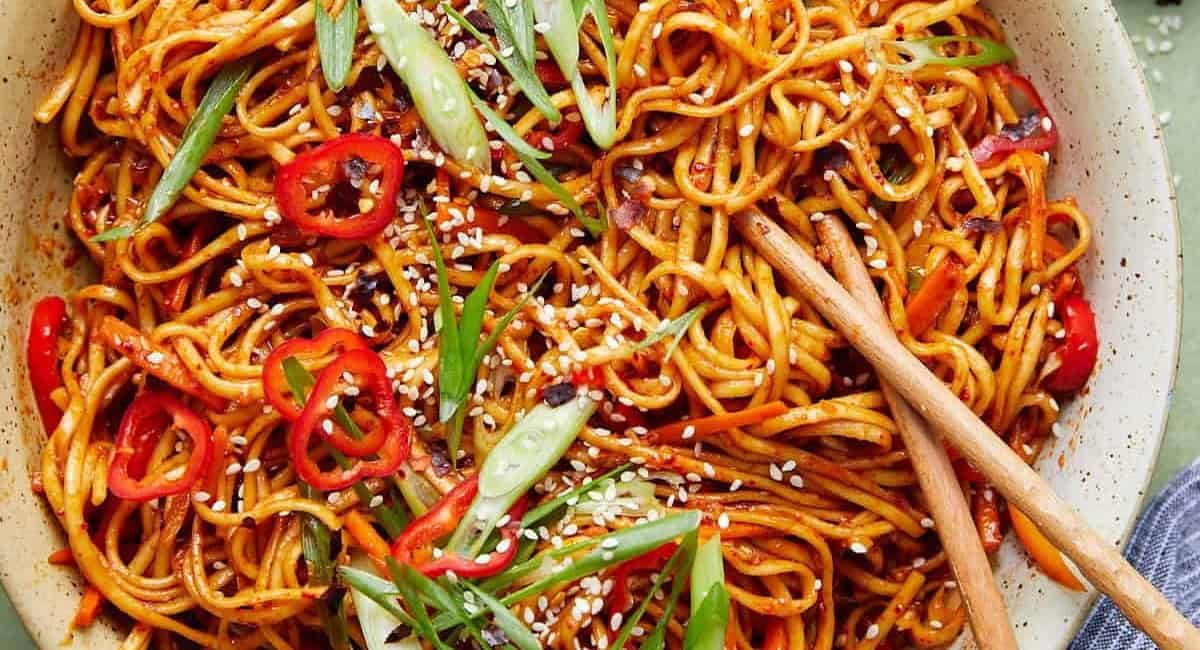 Overhead image of chili garlic noodles with garnish.