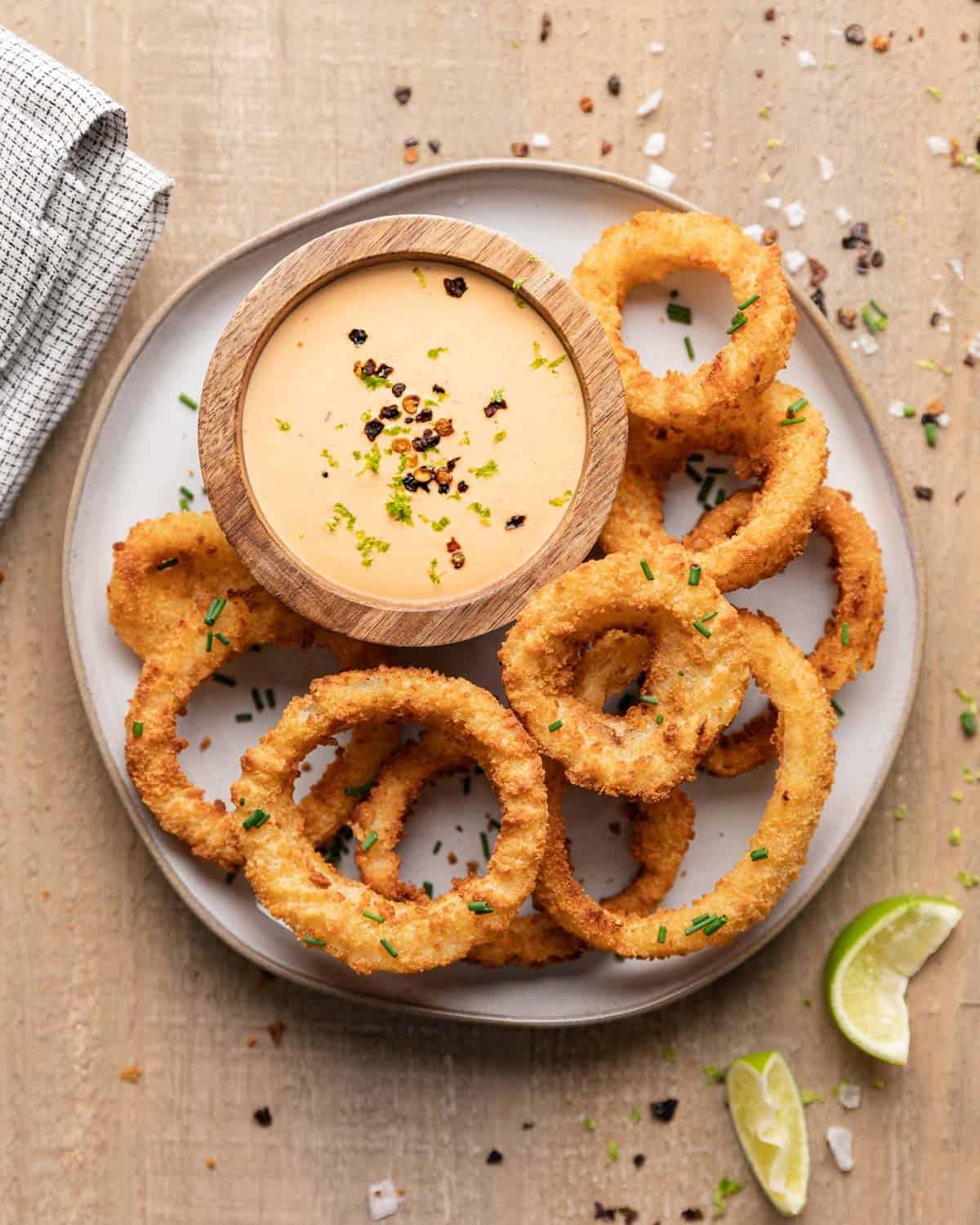 Overhead of onion rings and chipotle crema sauce on a plate.