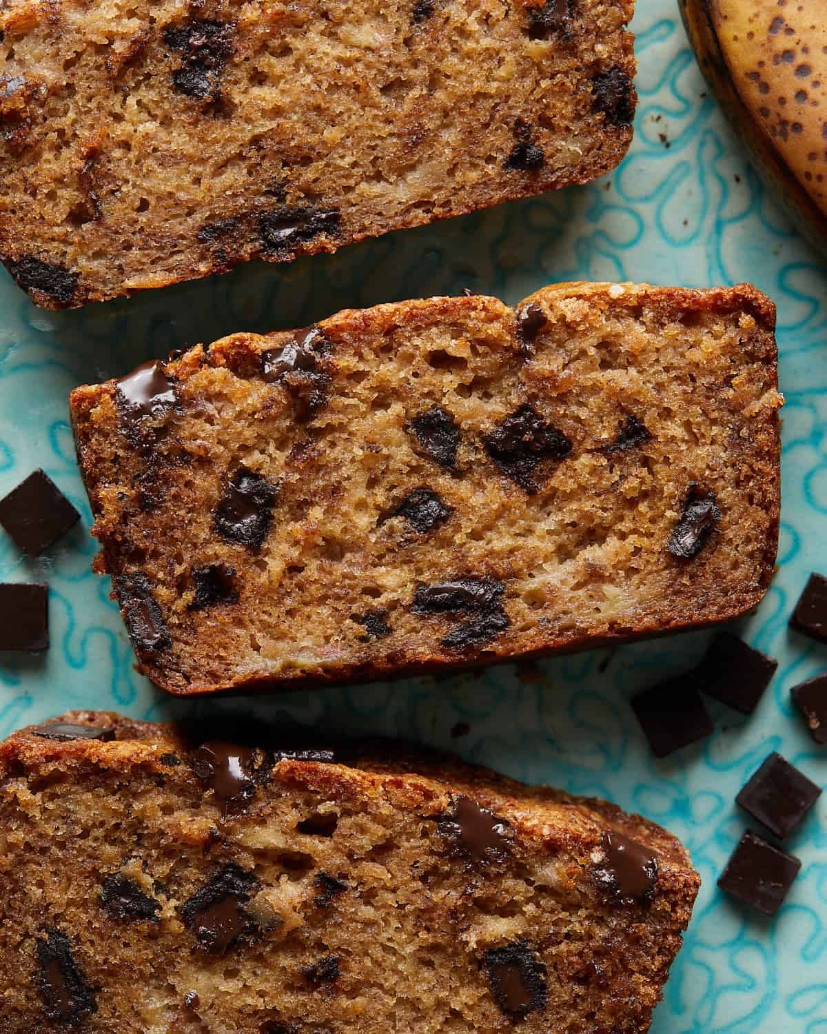 Overhead image of chocolate chunk banana bread sliced on blue plate.