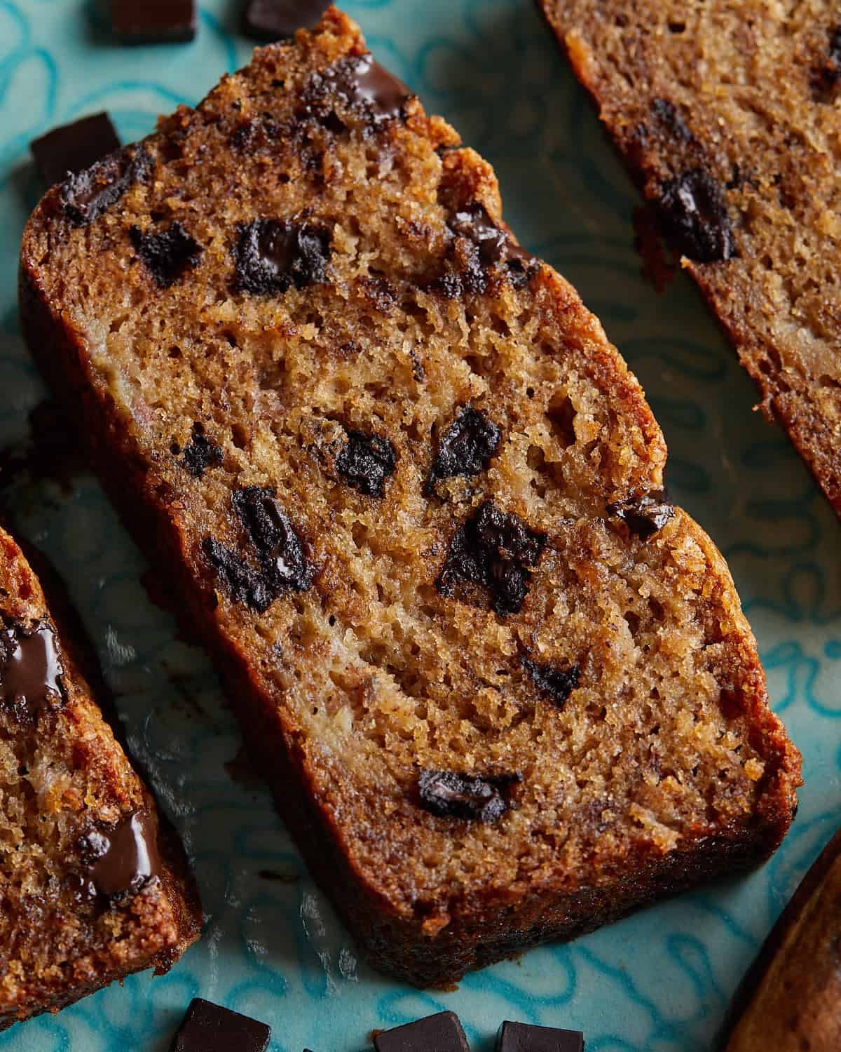 Up close overhead image of chocolate chunk banana bread on blue dish.