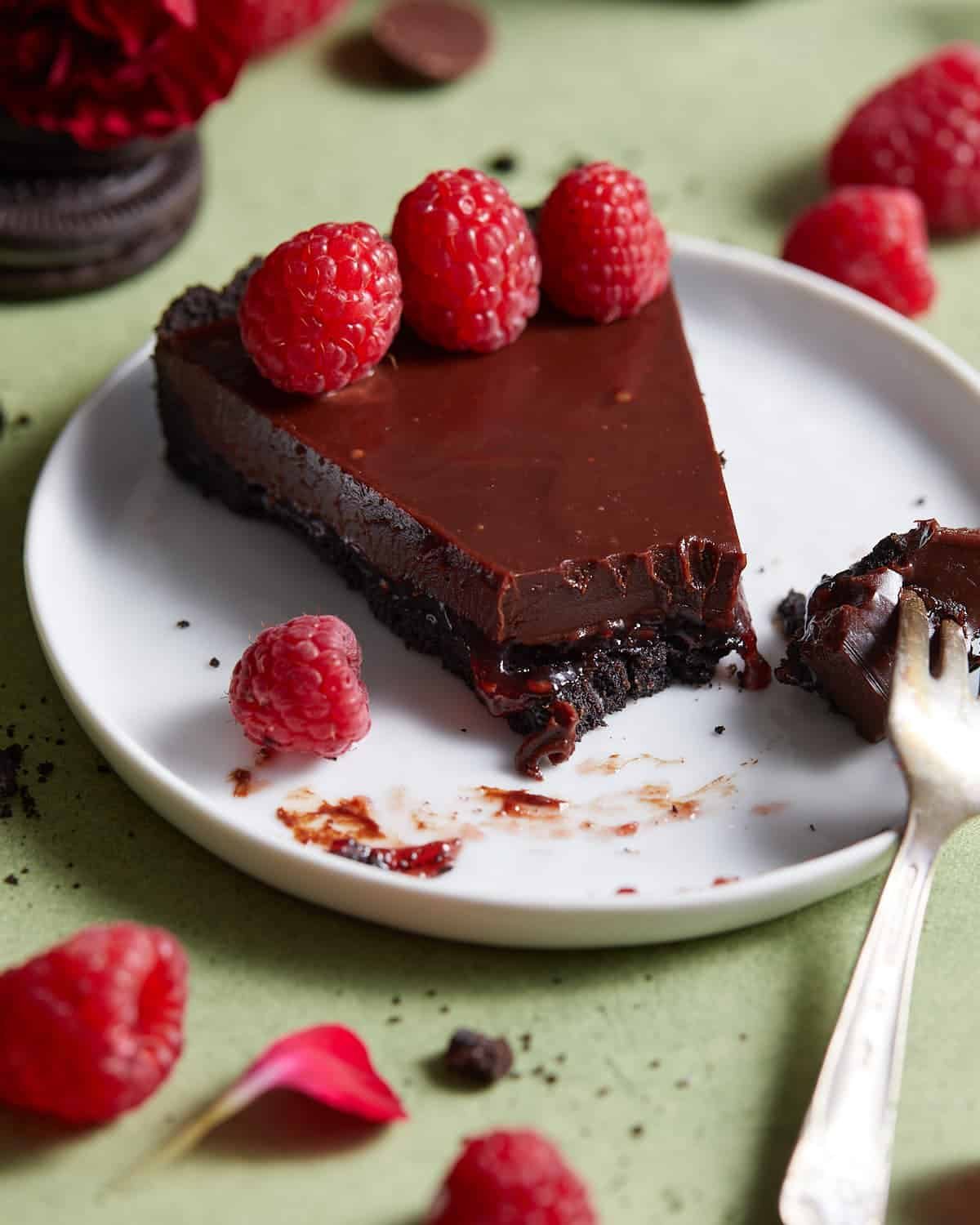Up close image of chocolate raspberry tart on white dish.